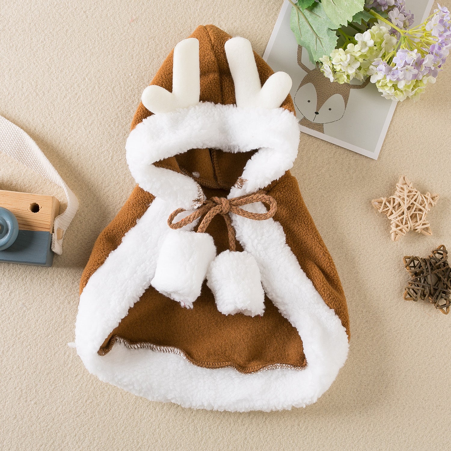 Children's hooded cloak with white fur trim on a beige surface
